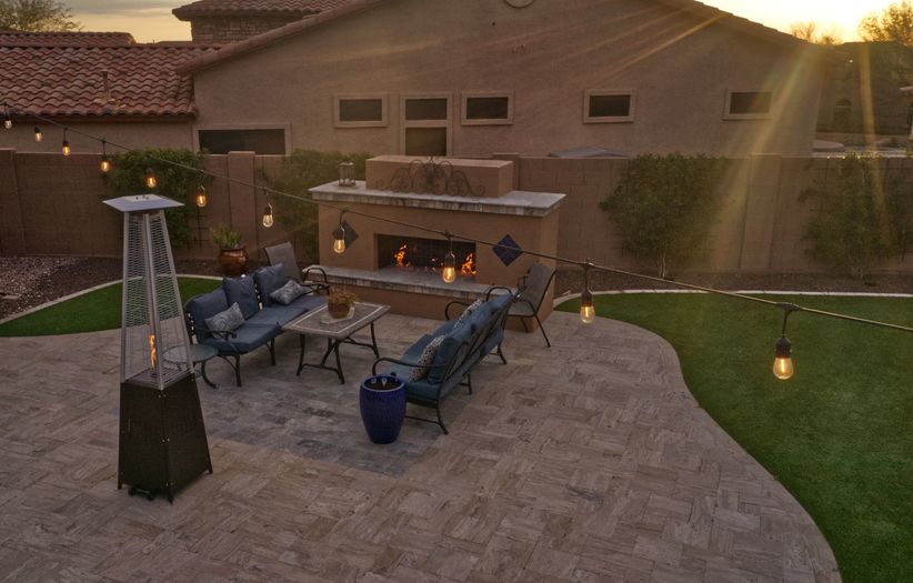 An aerial view of a desert landscaped backyard in Arizona featuring a travertine pool deck and fireplace.