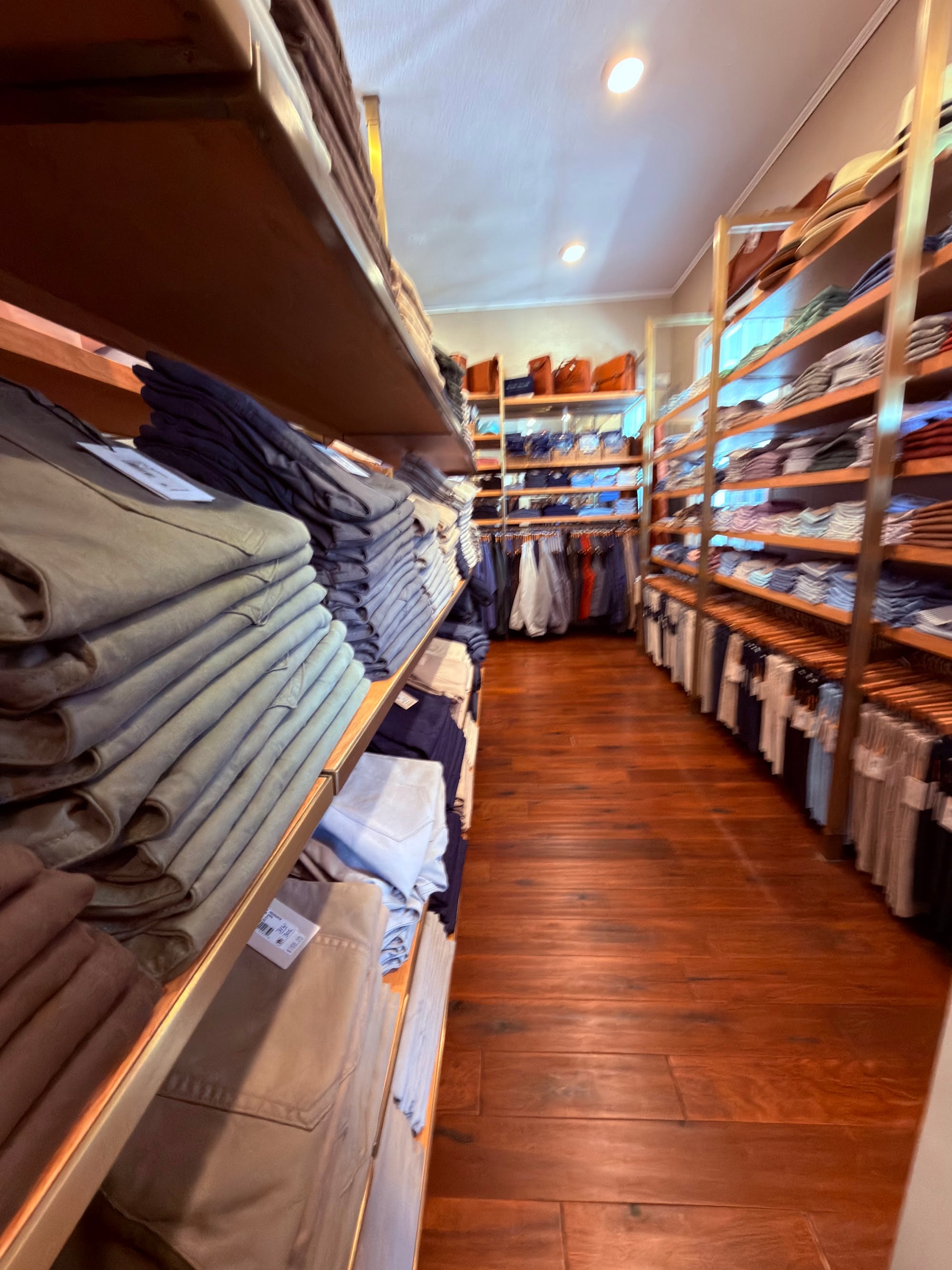 Wall of folded men's shirts and sweaters along the hardwood aisle of the Pawleys Island Men's Store