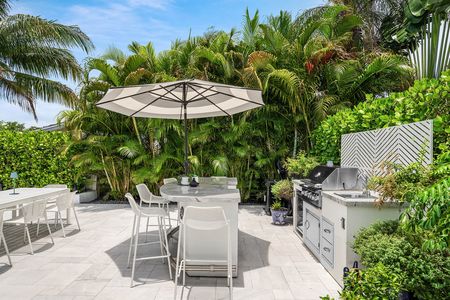 Outdoor kitchen and bar on Bianco marble patio and tropical landscaping at 3481 NE 18th Avenue Oakland Park FL