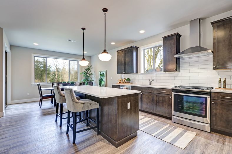 New kitchen boasts dark wood cabinets, white backsplash subway tile and over sized island