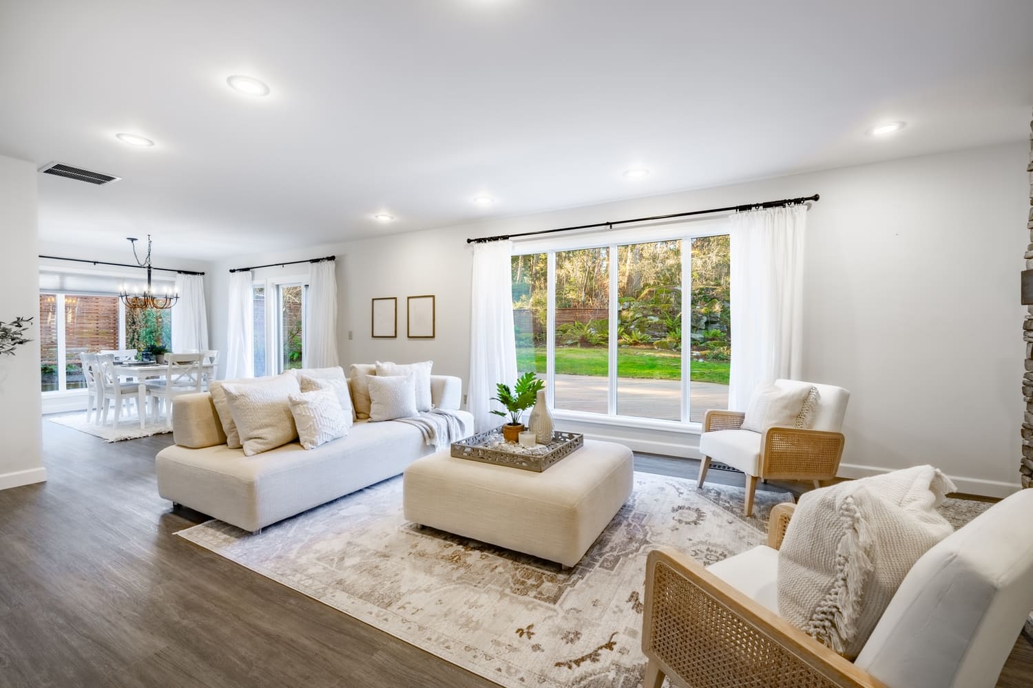 Interior living room with fireplace stone and wood mantle staircase wooden flooring decorated and staged large bright windows classic and modern decor