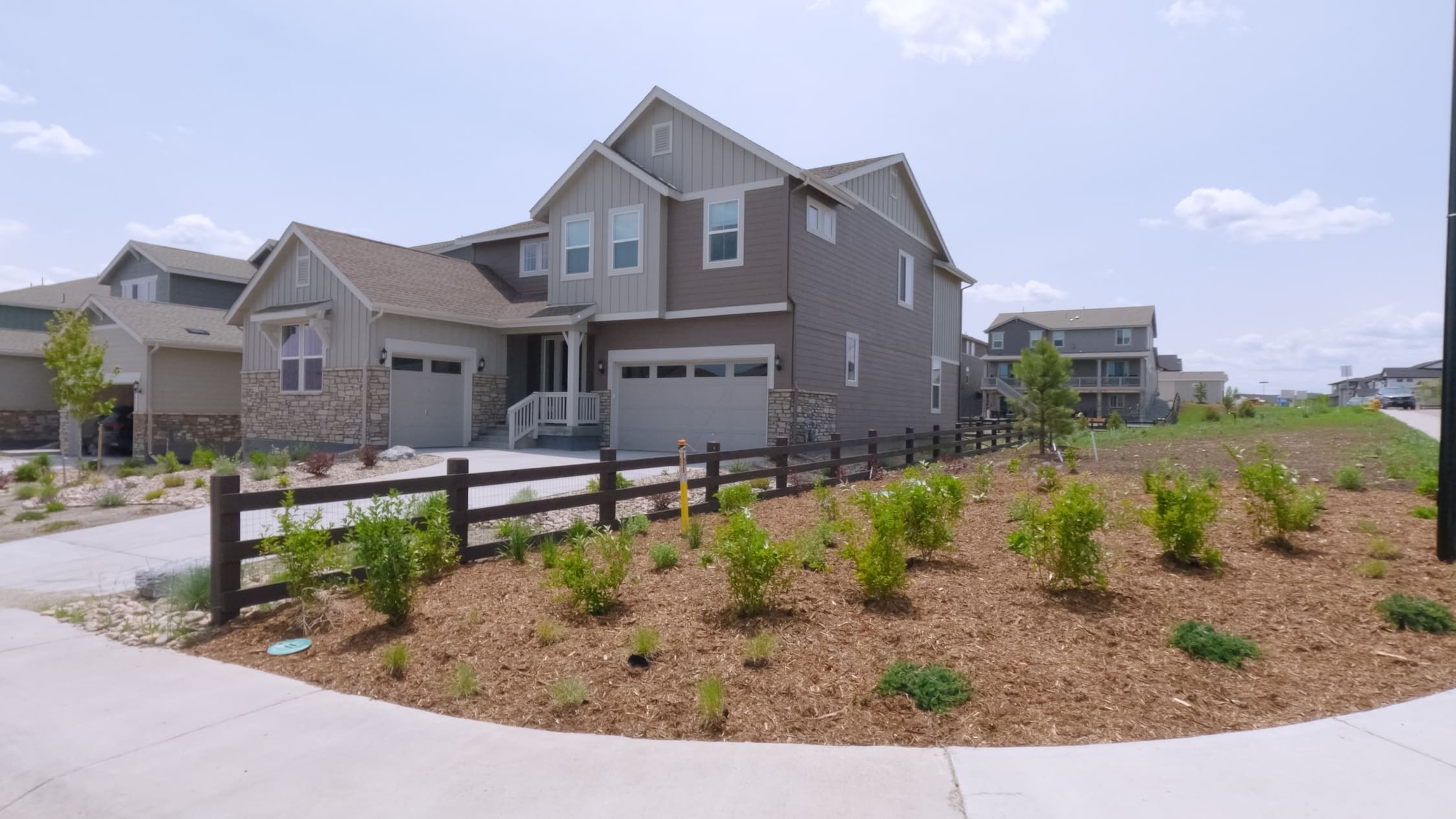 A modern two-story home in Castle Rock, Colorado with a split rail fence and freshly planted landscaping in front. The yard features mulch and newly seeded plants. (1) (1)
