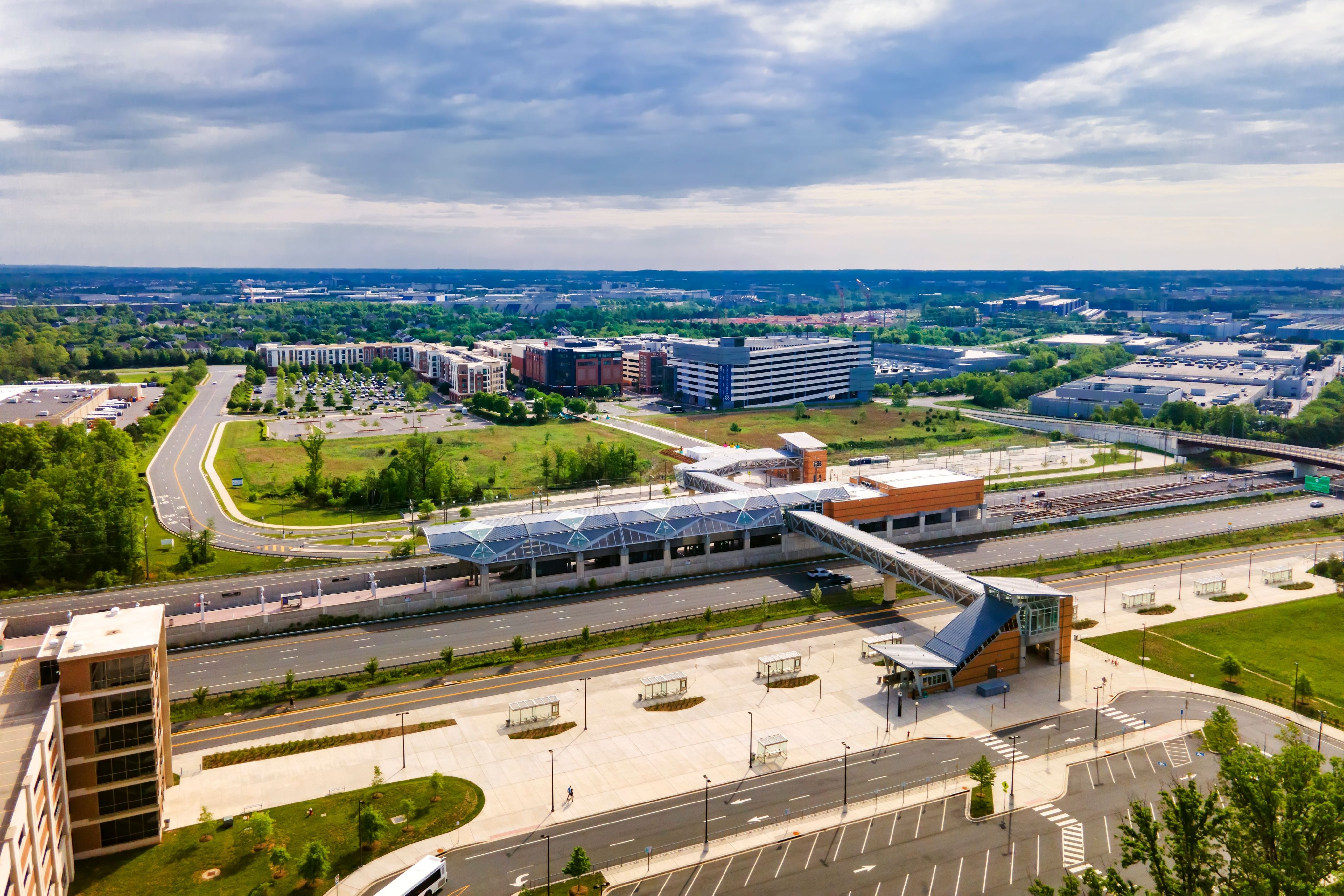 Above-ground subway station in Washington suburbs. Highways, parks and bus stops. Drone view.