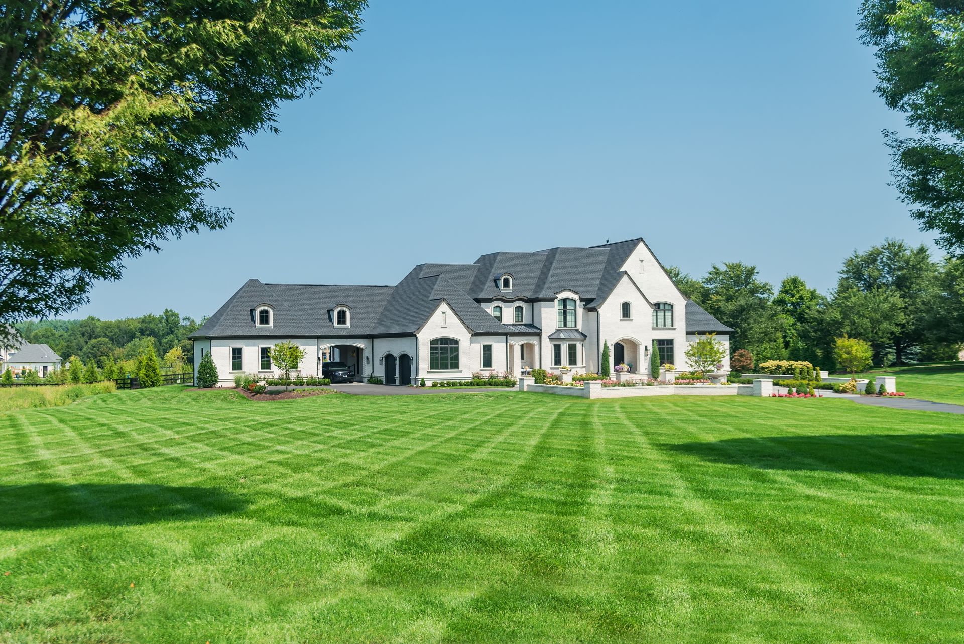 luxury country home in the suburbs of Washington, DC. Landscaped with a large lawn and blue skies. (1)