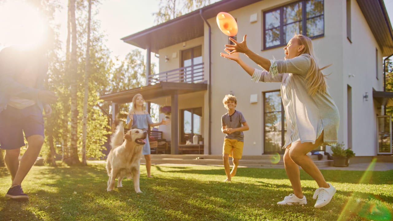 Beautiful Family of Four Play Catch Toy Ball with Happy Golden Retriever Dog on the Backyard Lawn. Idyllic Family Has Fun with Loyal Pedigree Dog Outdoors in Summer House Backyard. (1) (1)