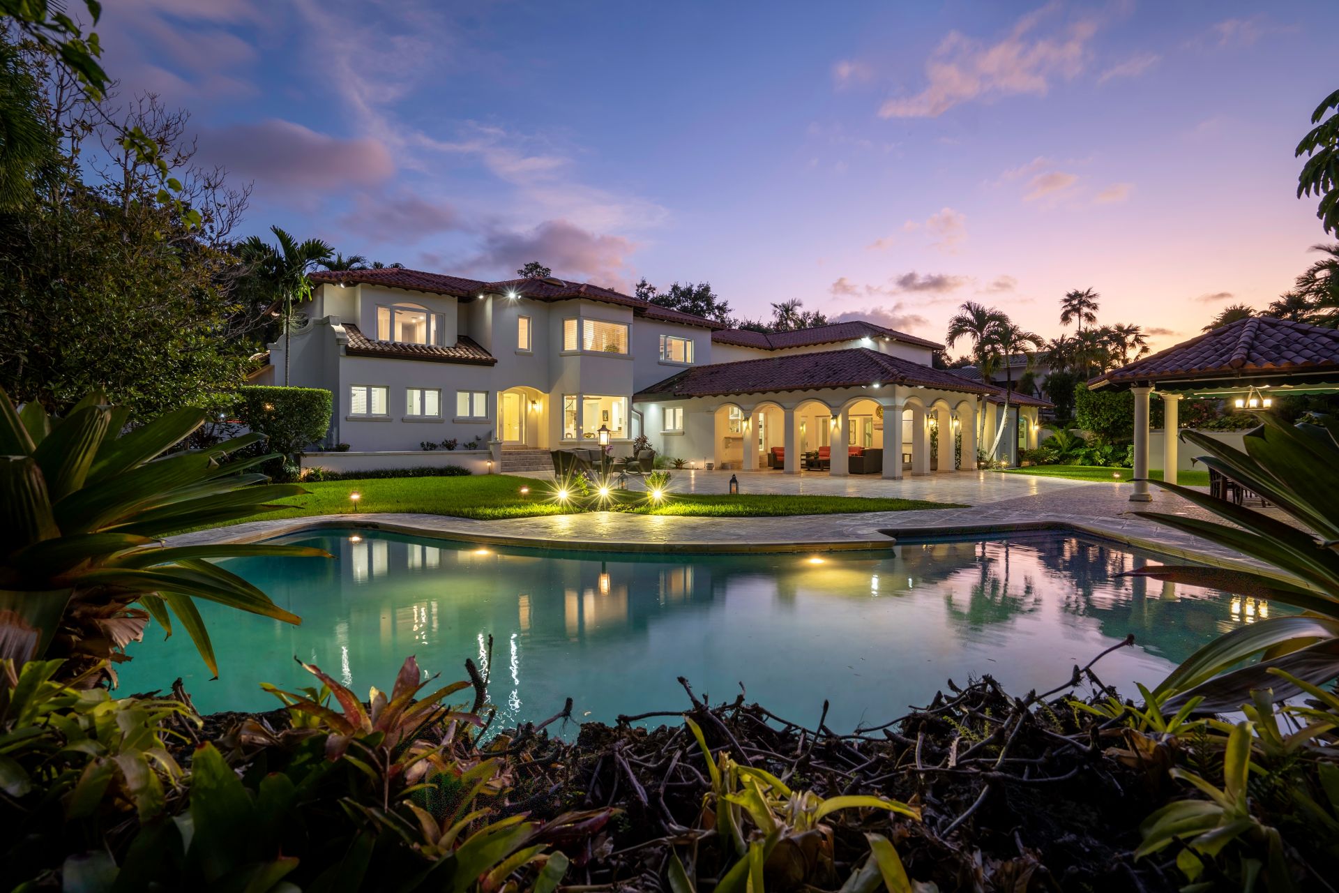 Florida, USA. January Backyard of a modern house with swimming pool, artificial grass, stone path, trees, chairs and an umbrella.