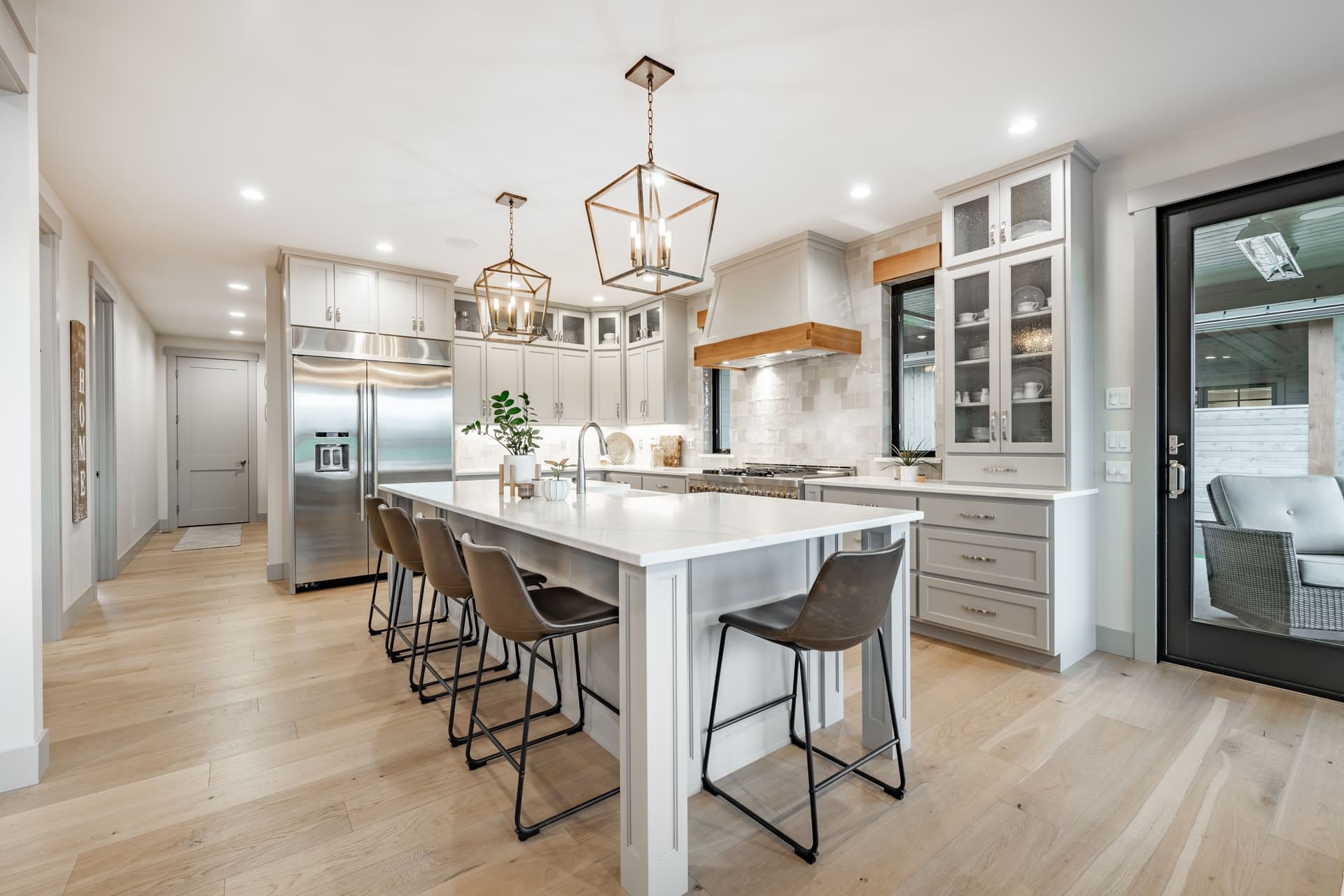 Interior modern farmhouse kitchen and dining room with white countertops bar stools large dining table stainless appliances and view to living room with vaulted ceiling (2)