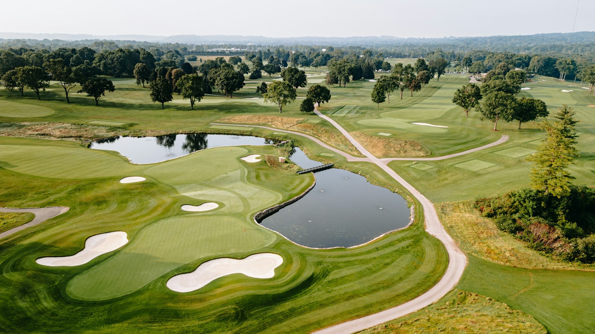Aerial view of championship golf fairways, bunkers and water framed by mature trees
