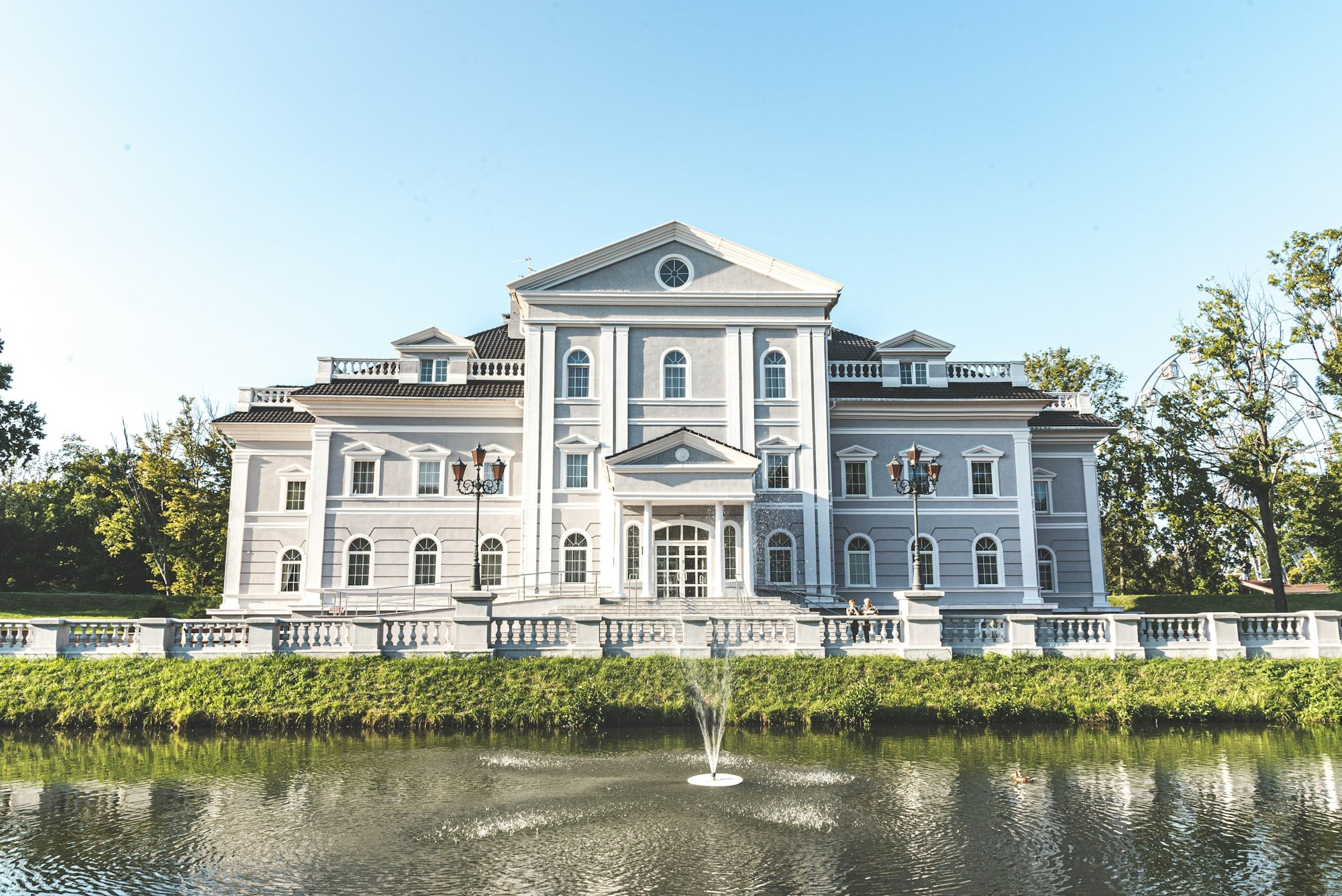 Classical white estate with columned portico and reflecting pond