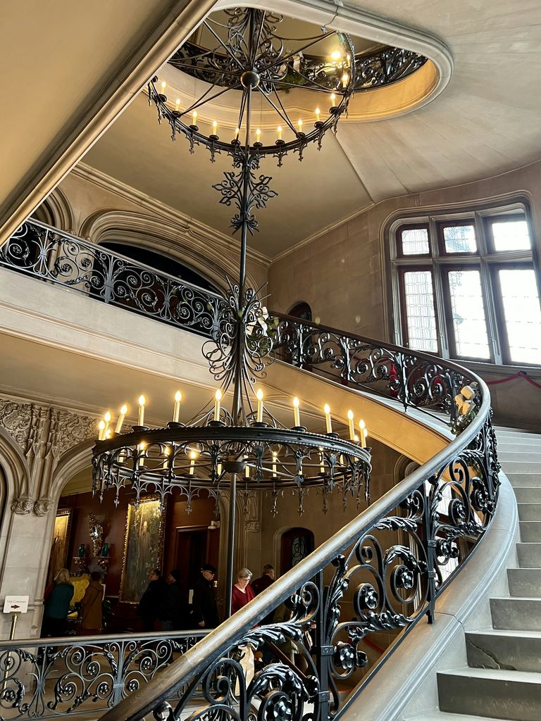 Curved staircase with wrought-iron balustrade and candle chandelier