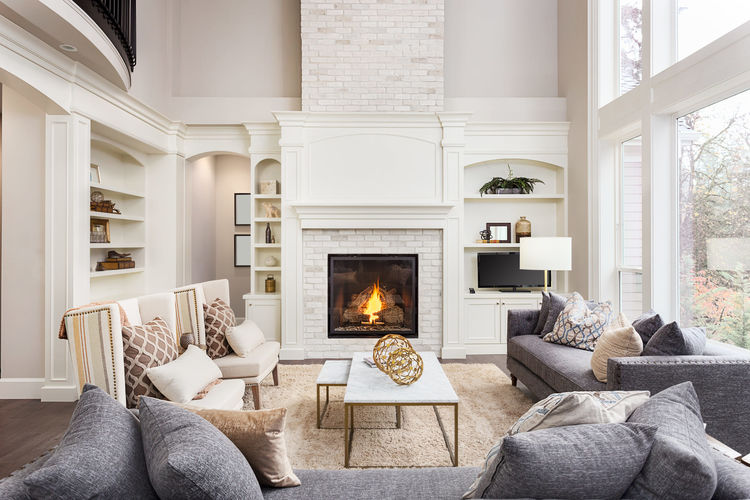 Beautiful living room interior with hardwood floors and fireplace in new luxury home. Large bank of windows hints at exterior view (1) (1)