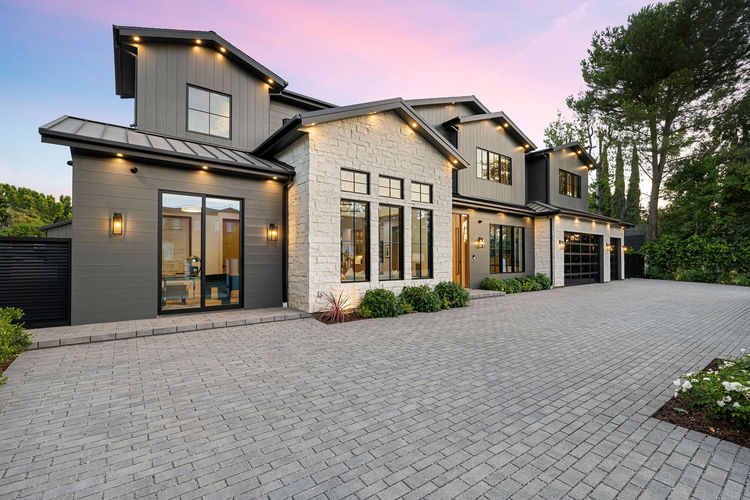 Modern luxury home exterior with a spacious driveway and well-lit facade at sunset. (1) (1) (1)
