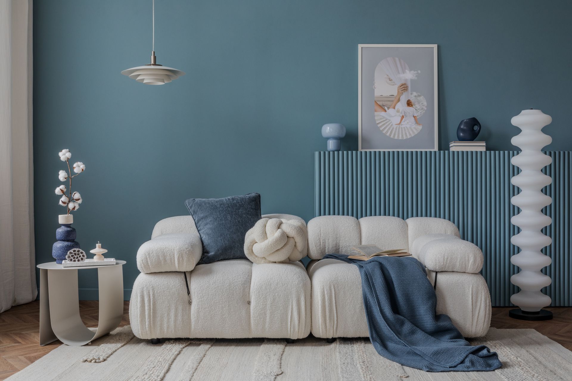 Minimalist interior with a boucle sofa, blue accents, and artistic decor, creating a tranquil and stylish atmosphere. (1)