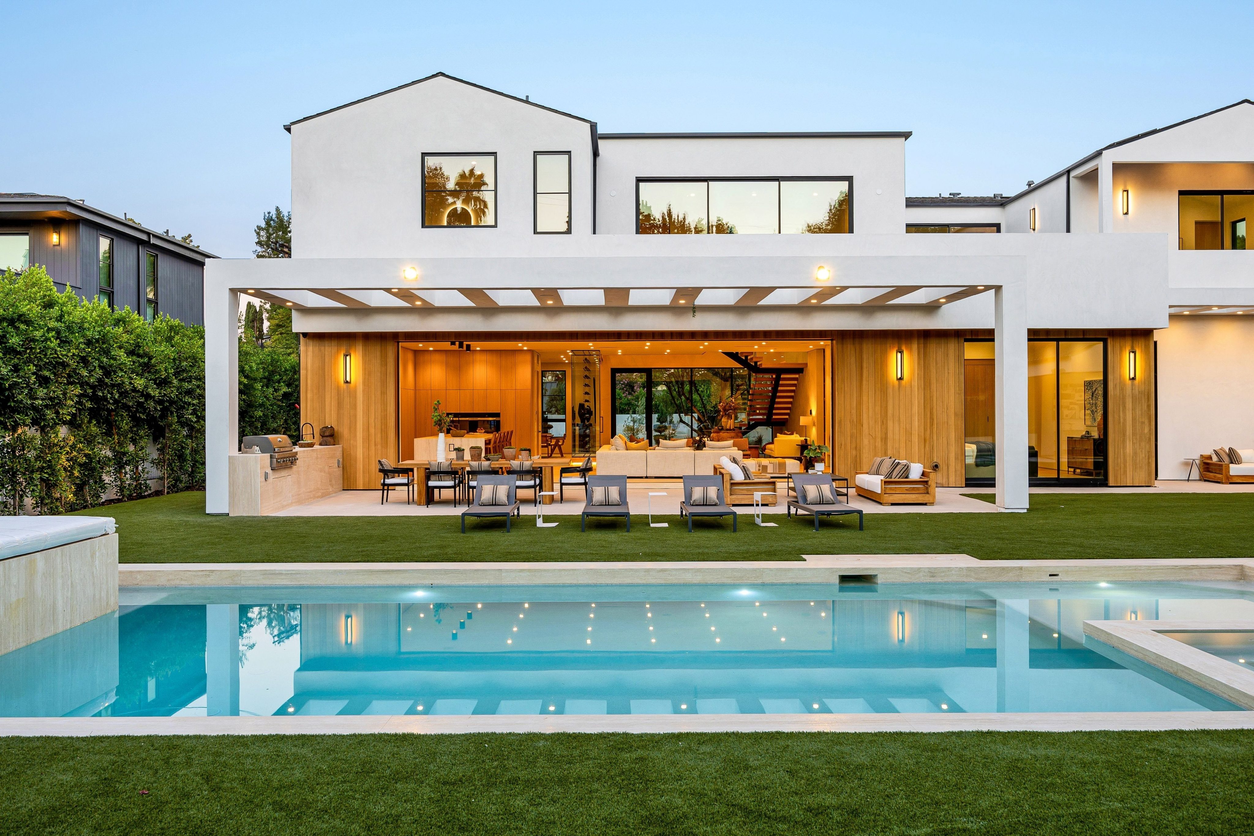 Modern luxury home with a spacious patio and pool at dusk, showcasing elegant architecture and outdoor living space.