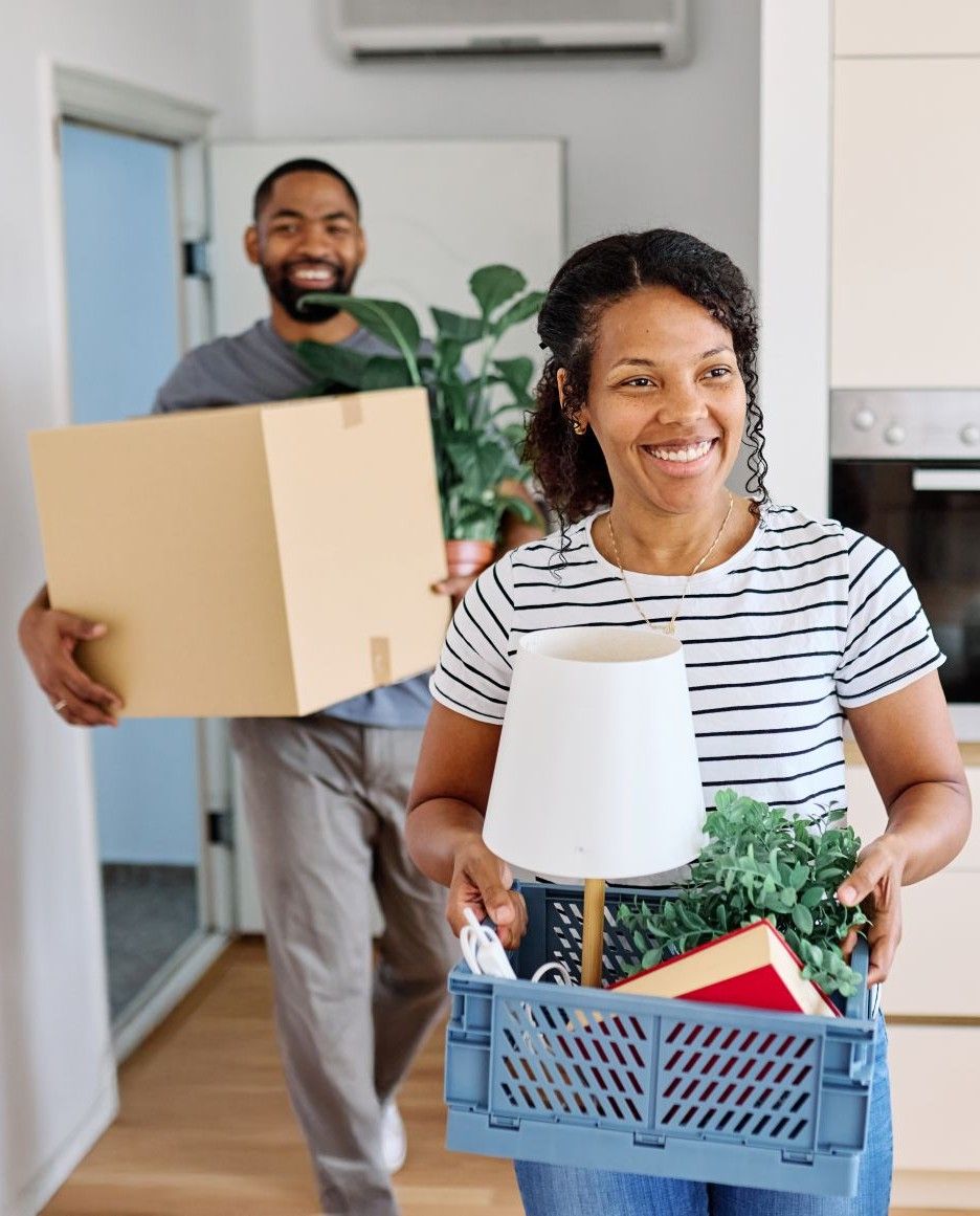 Young black couple moving into a new modern house, carrying boxes and arriving home together.