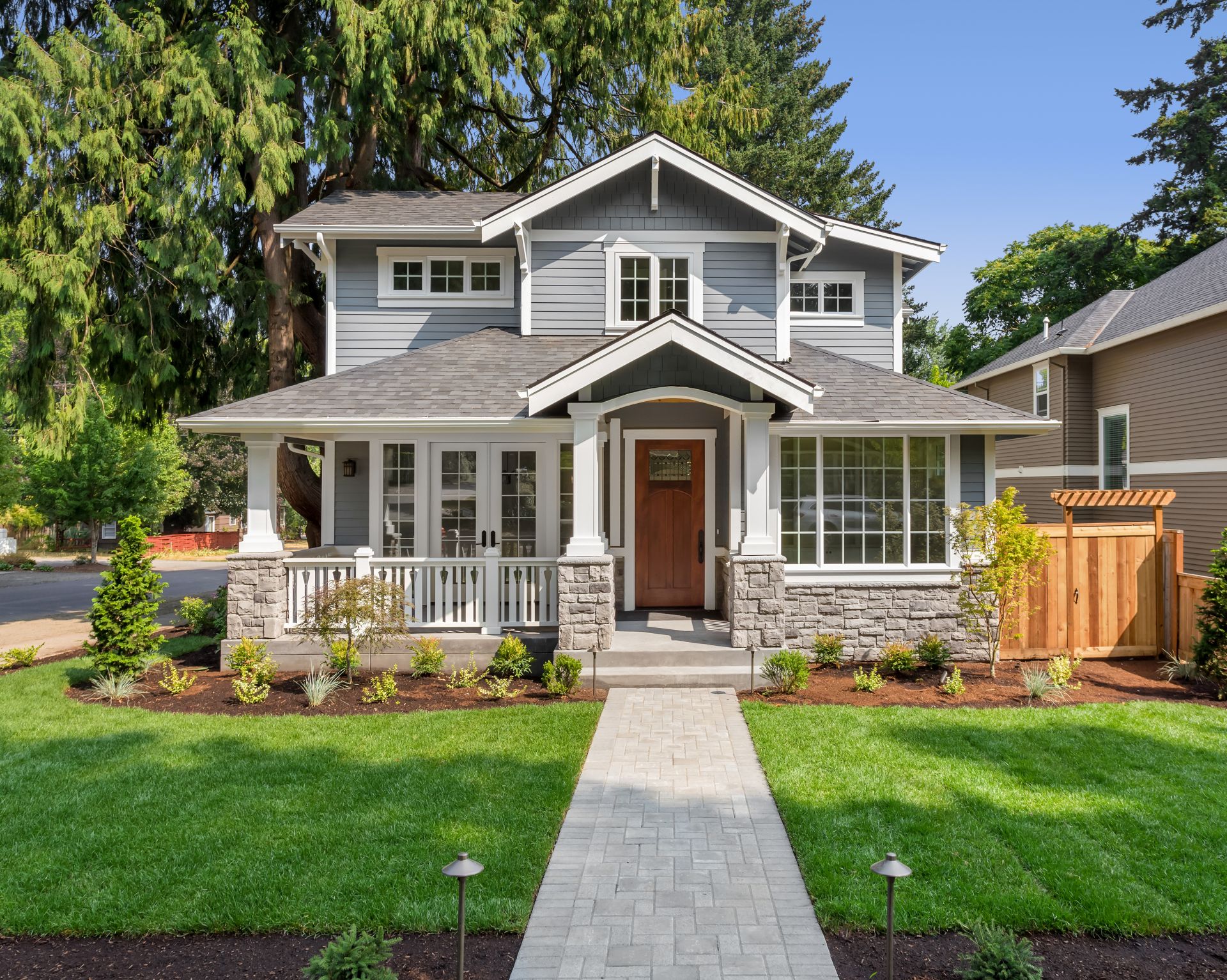 Beautiful new home exterior with covered porch and green grass on bright sunny day with blue sky