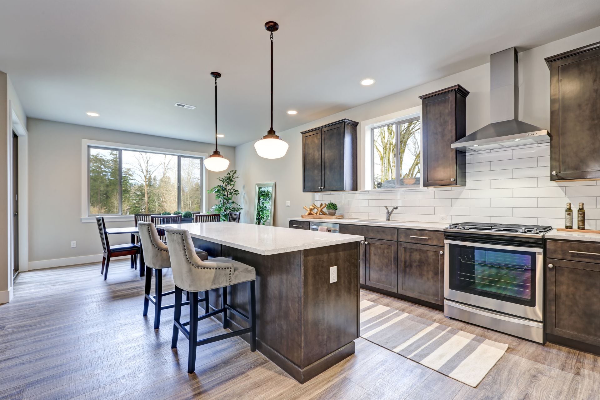New kitchen boasts dark wood cabinets, white backsplash subway tile and over sized island