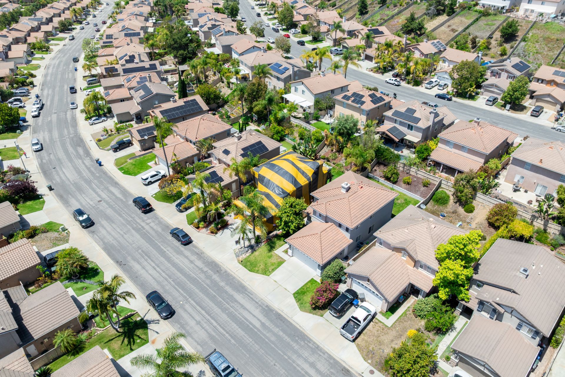 Aerial view of yellow and gray termite tent on a big house in San Diego, South California