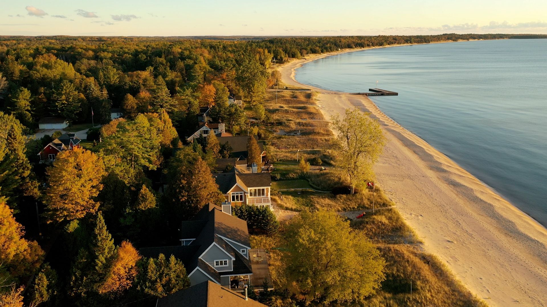 Aerial view of beachfront houses. Establishing shot of waterfront homes. Sunset sunrise sunlight, Fall Autumn colorful trees. Midwest USA, Door county Wisconsin, lake Michigan.