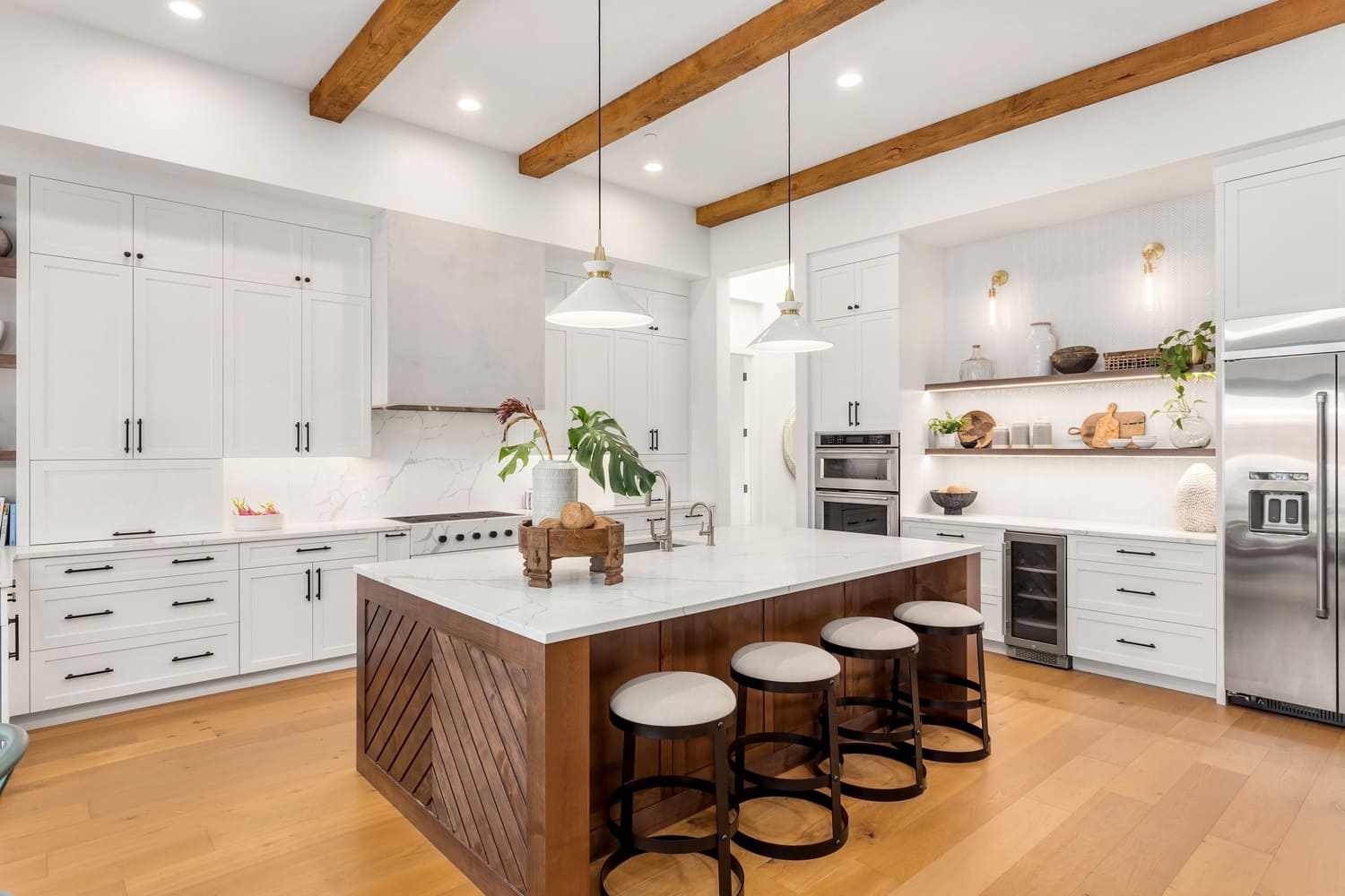 Beautiful white kitchen in new luxury home with large island. Features large island, stainless steel appliances, and sleek modern range hood.