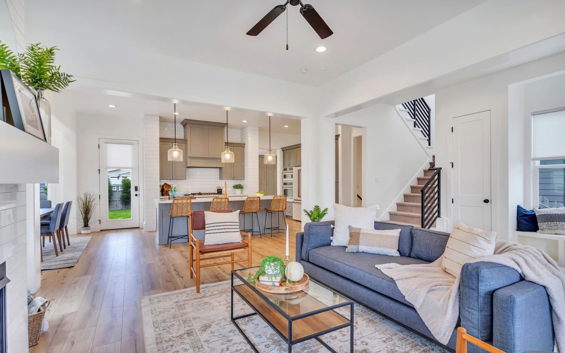 Open-concept living room and kitchen with staircase and neutral furnishings