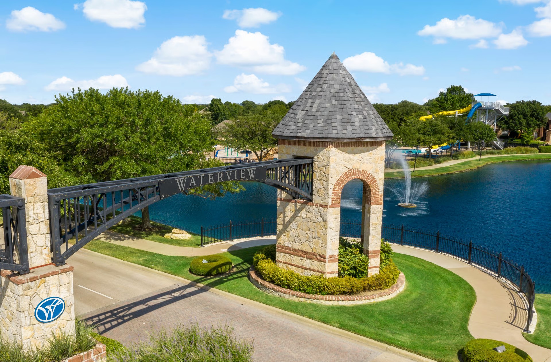Waterview community entrance sign and stone tower overlooking a lake and pool in Rowlett, TX
