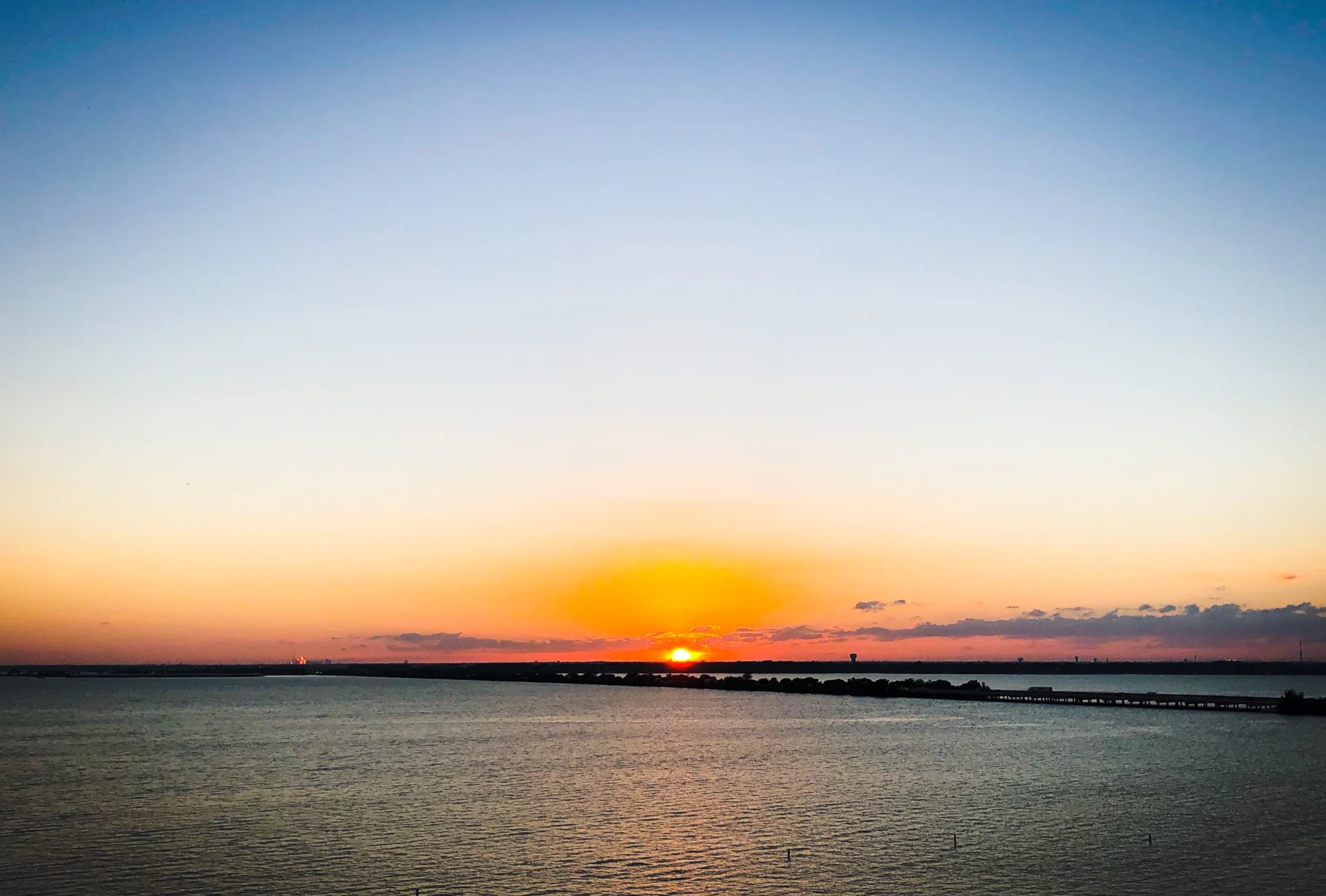 Sunset over Lake Ray Hubbard in Rockwall, TX with calm water and a distant causeway