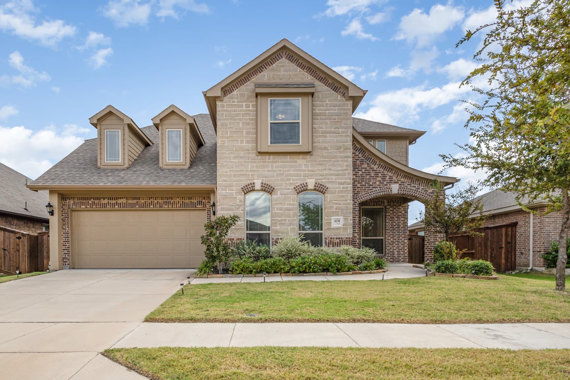 Two-story brick and stone home with dormer windows at 4130 Lagoon Place, Waterscape, Royse City TX