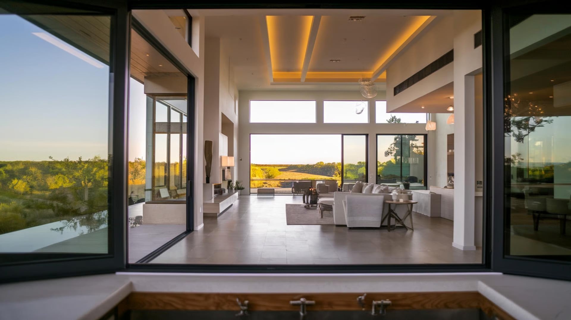 Open-concept living room with floor-to-ceiling sliding glass doors opening to a scenic outdoor view at sunset