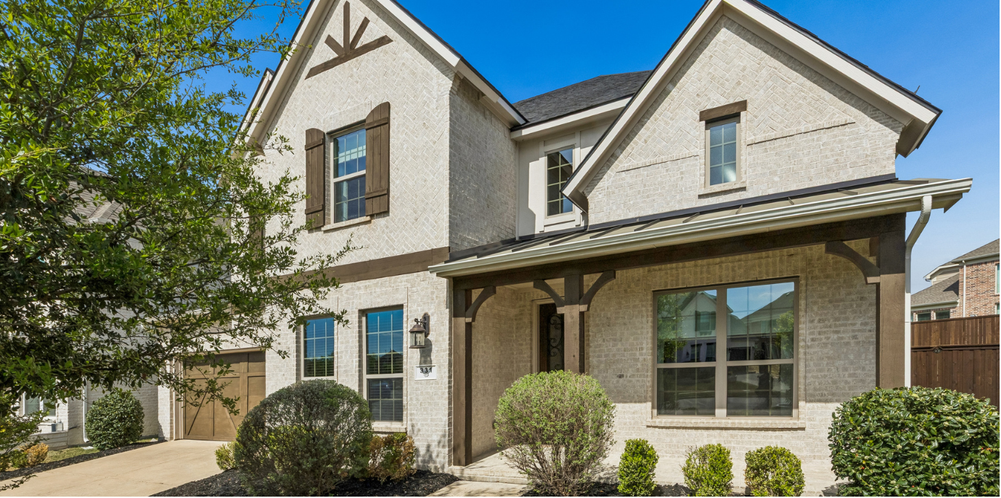 Light brick two-story home with covered front porch and shutters in Wylie, Texas
