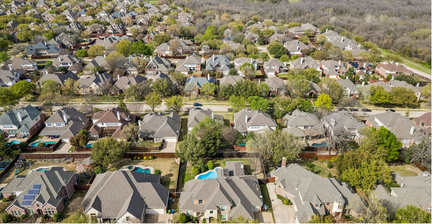 Aerial view of an established Wylie neighborhood with mature trees, pools, and greenbelt