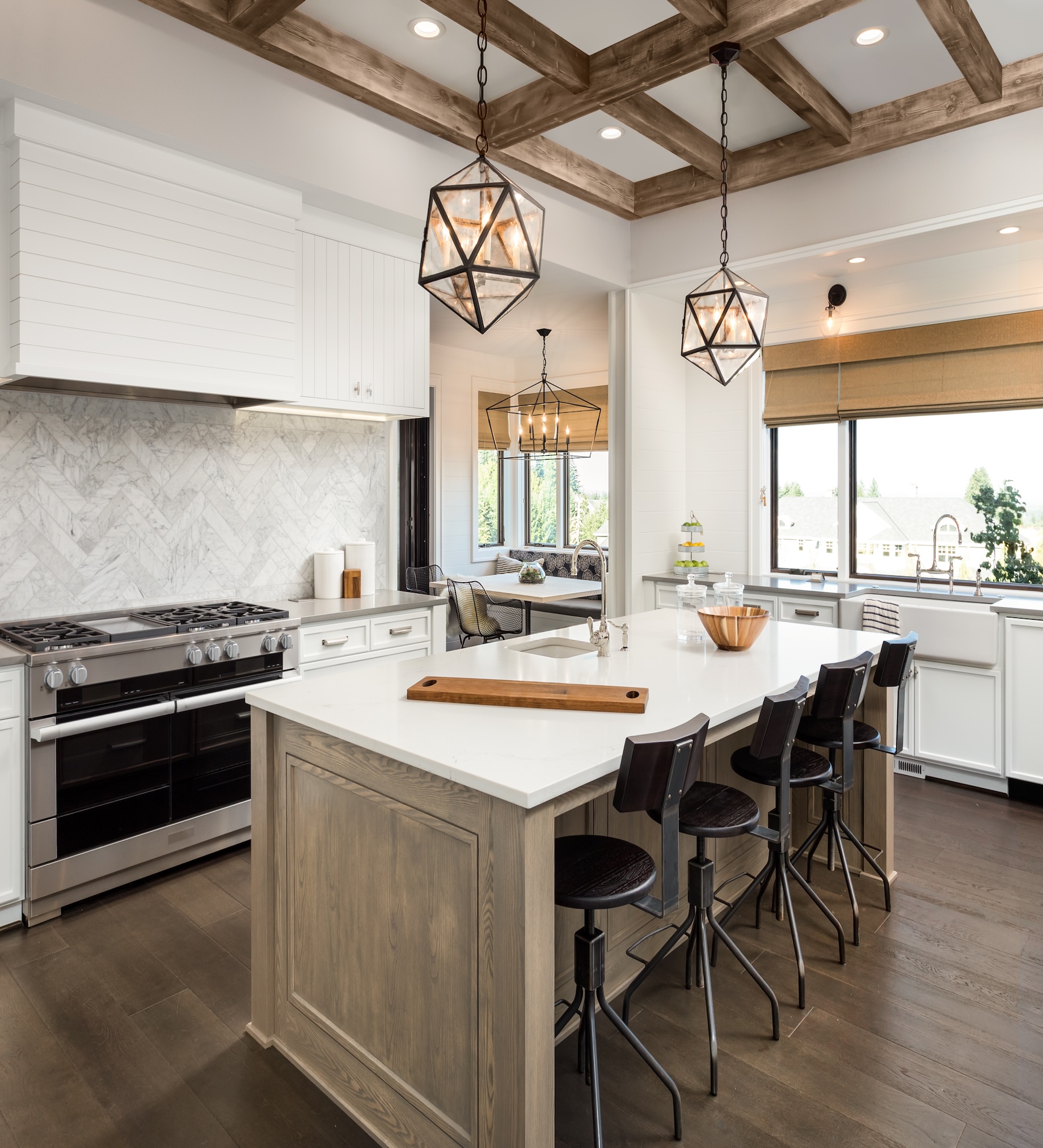 Open kitchen with a quartz-topped island and barstools, marble herringbone backsplash, stainless range, and exposed wood ceiling beams