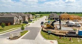 New home under construction with concrete foundation work in a growing residential neighborhood