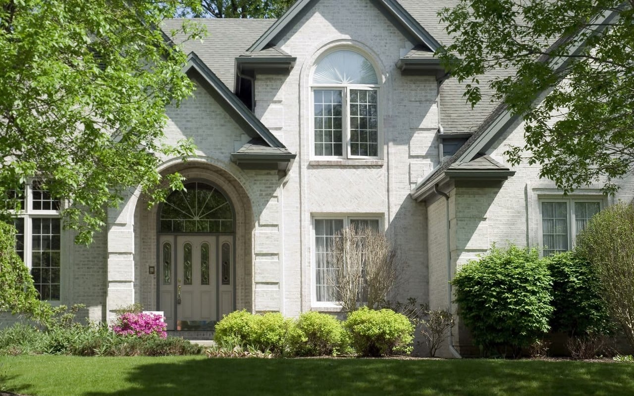 Two-story brick home with arched entryway and mature landscaping, used to illustrate the spring 2026 DFW housing market update