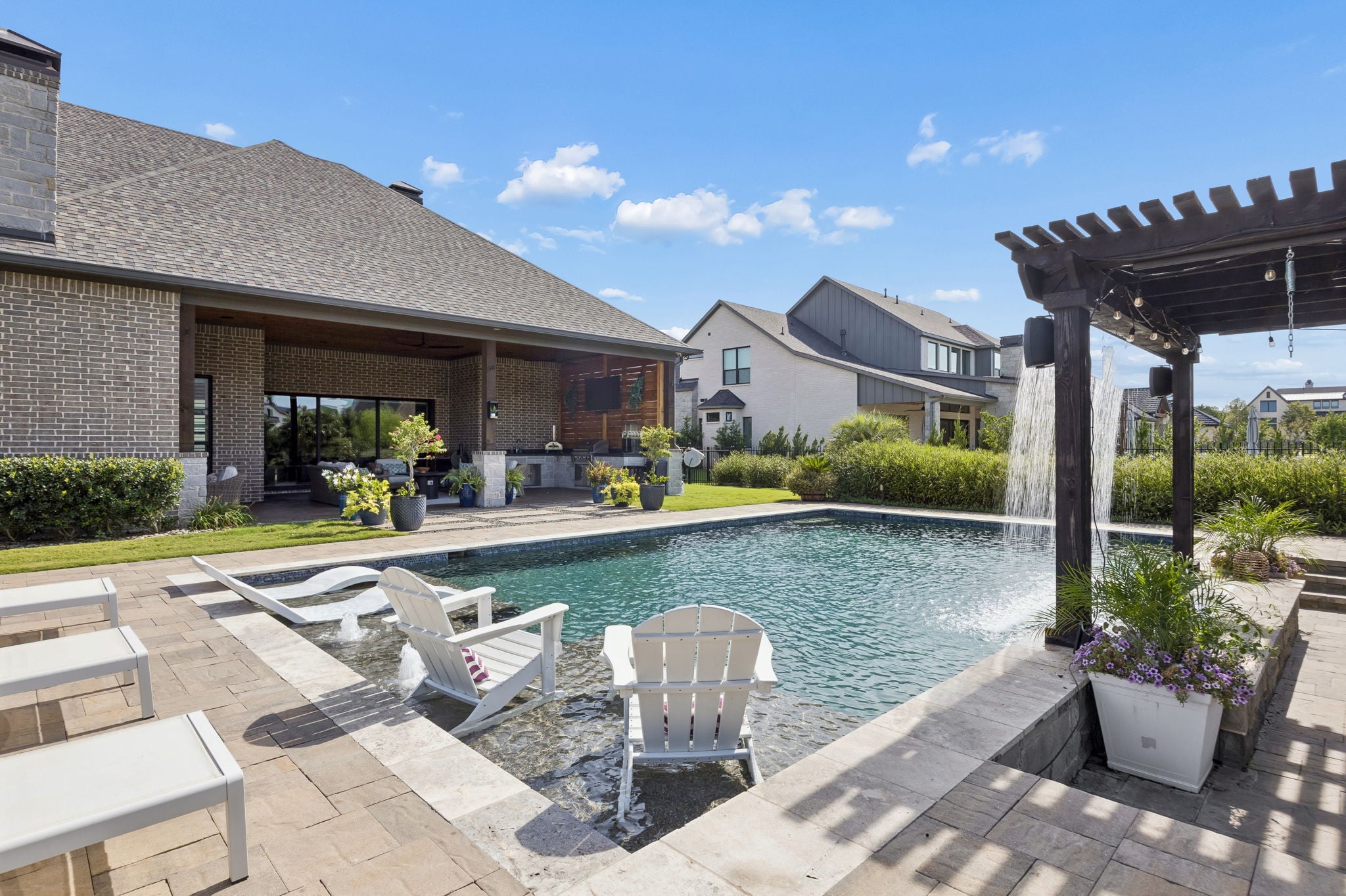Backyard pool with a tanning ledge, water feature, and covered outdoor living area at a North Texas home