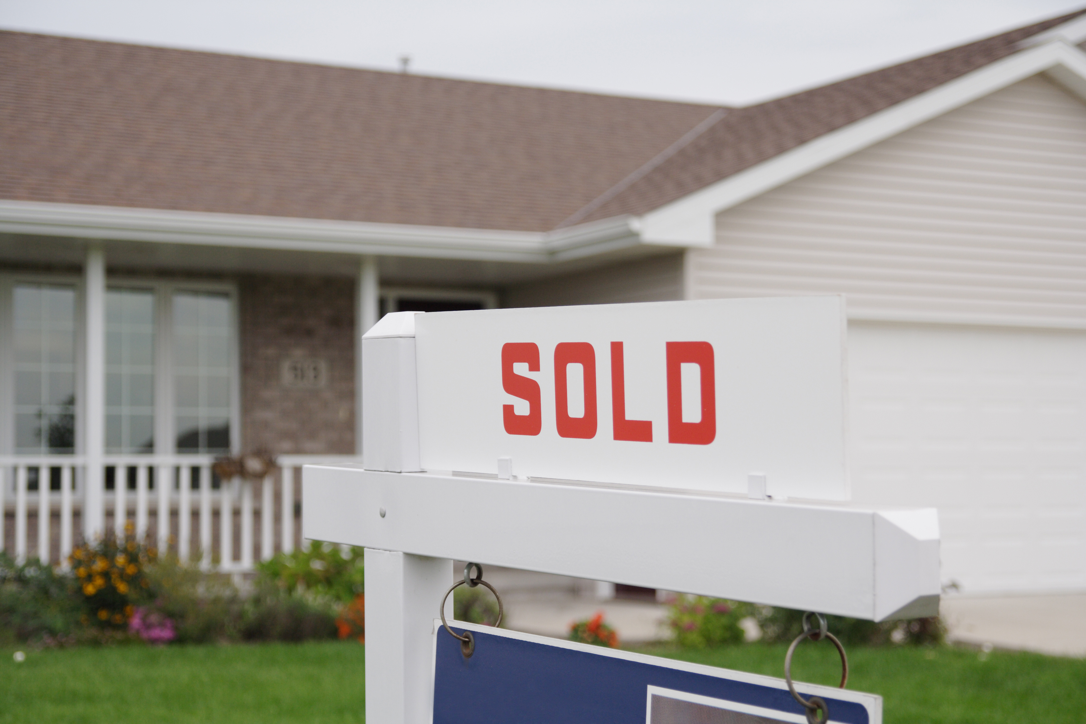 A sold sign in front of a single story brick home