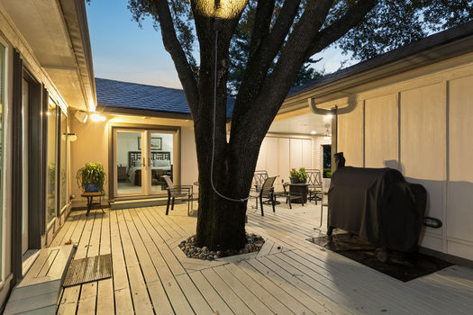 Courtyard deck with live oak and grill area at dusk | 9020 Glen Springs Dr, Dallas, TX 75243 | Lake Highlands