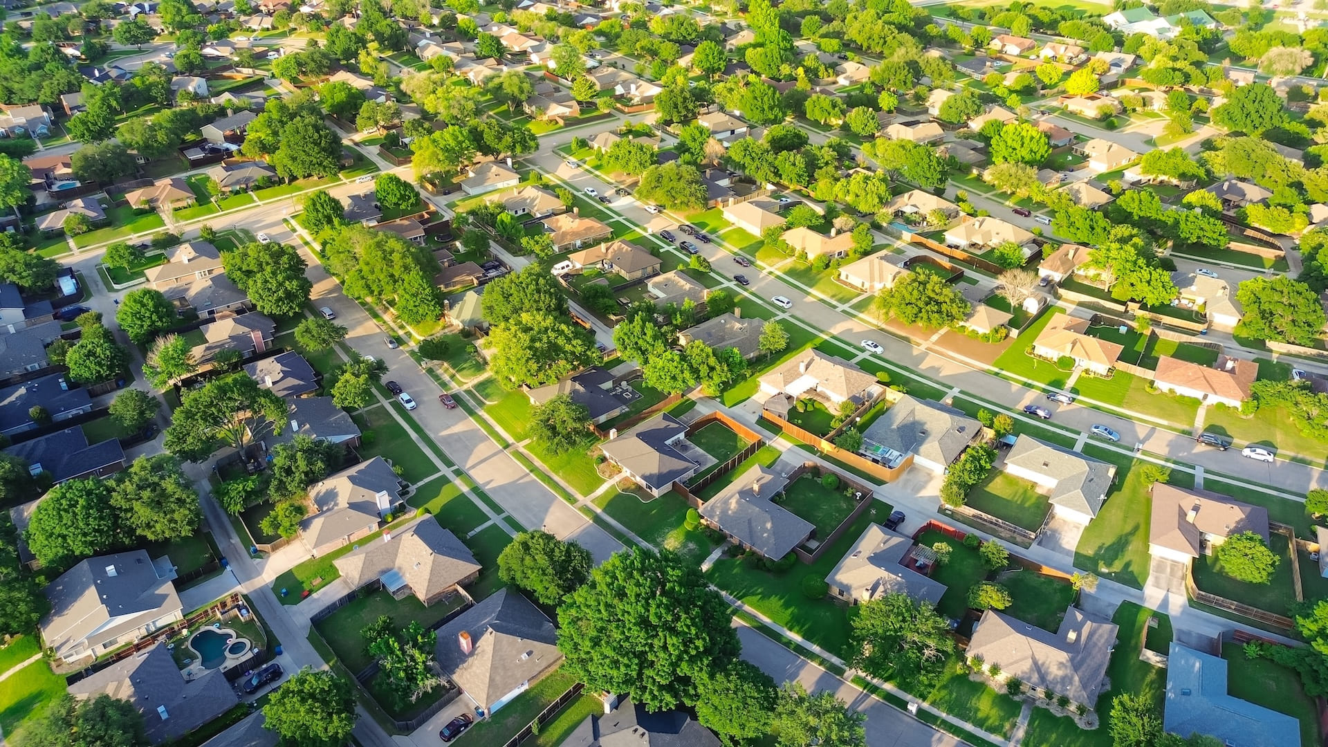 Parallel residential streets with back alleys and row of single-family houses surrounding by lush green trees in suburbs Dallas Fort Worth metro complex, suburban homes swimming pool, aerial. USA