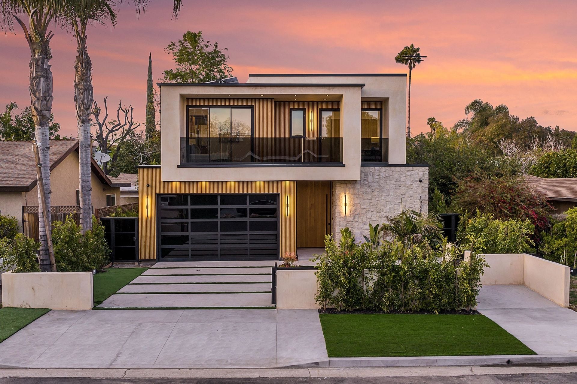 Modern two-story house with a sleek design and well-maintained garden at sunset.