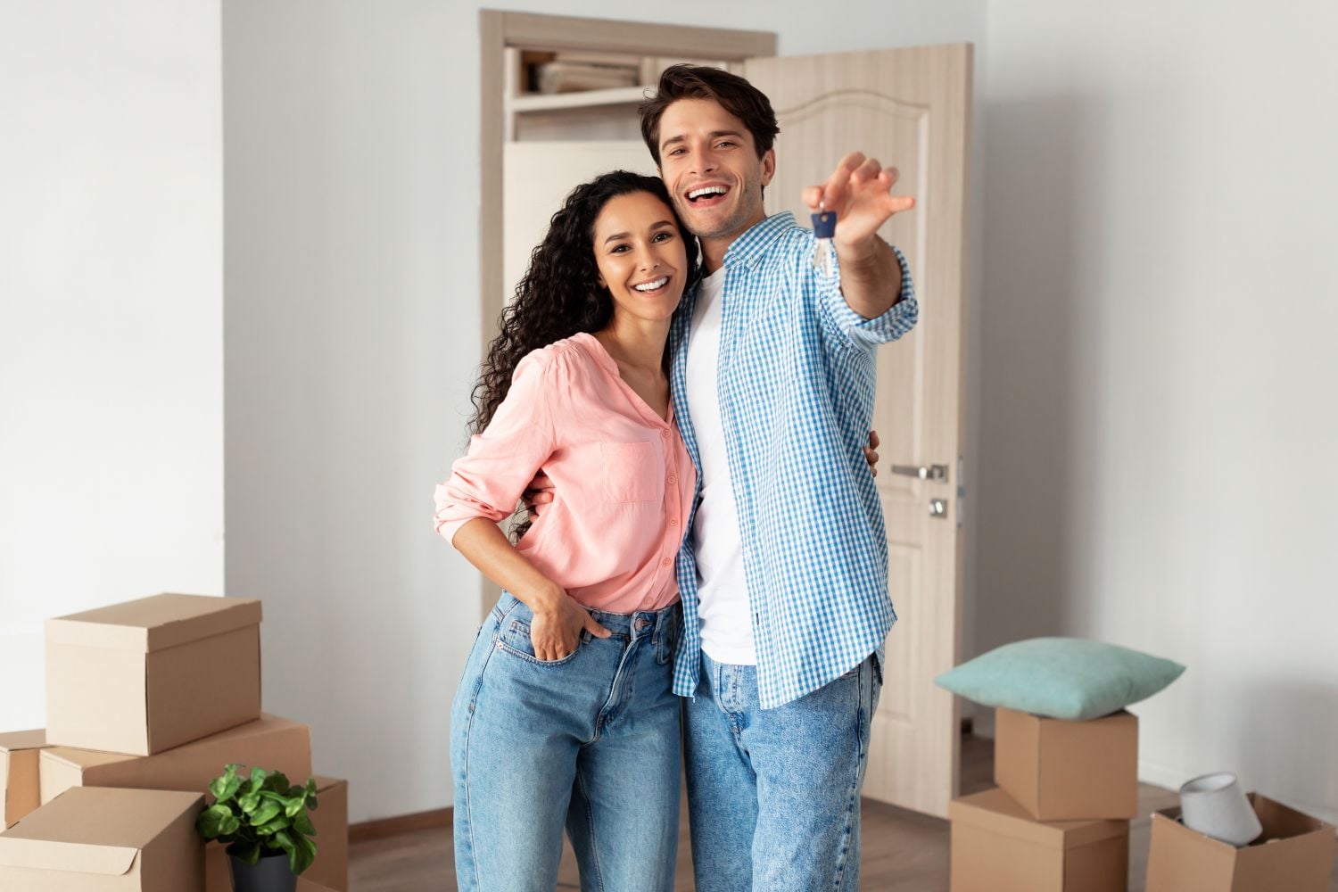 House Ownership. Portrait Of Happy Young Couple Holding Showing Key Standing In New Flat, Cheerful Guy And Lady Posing Hugging