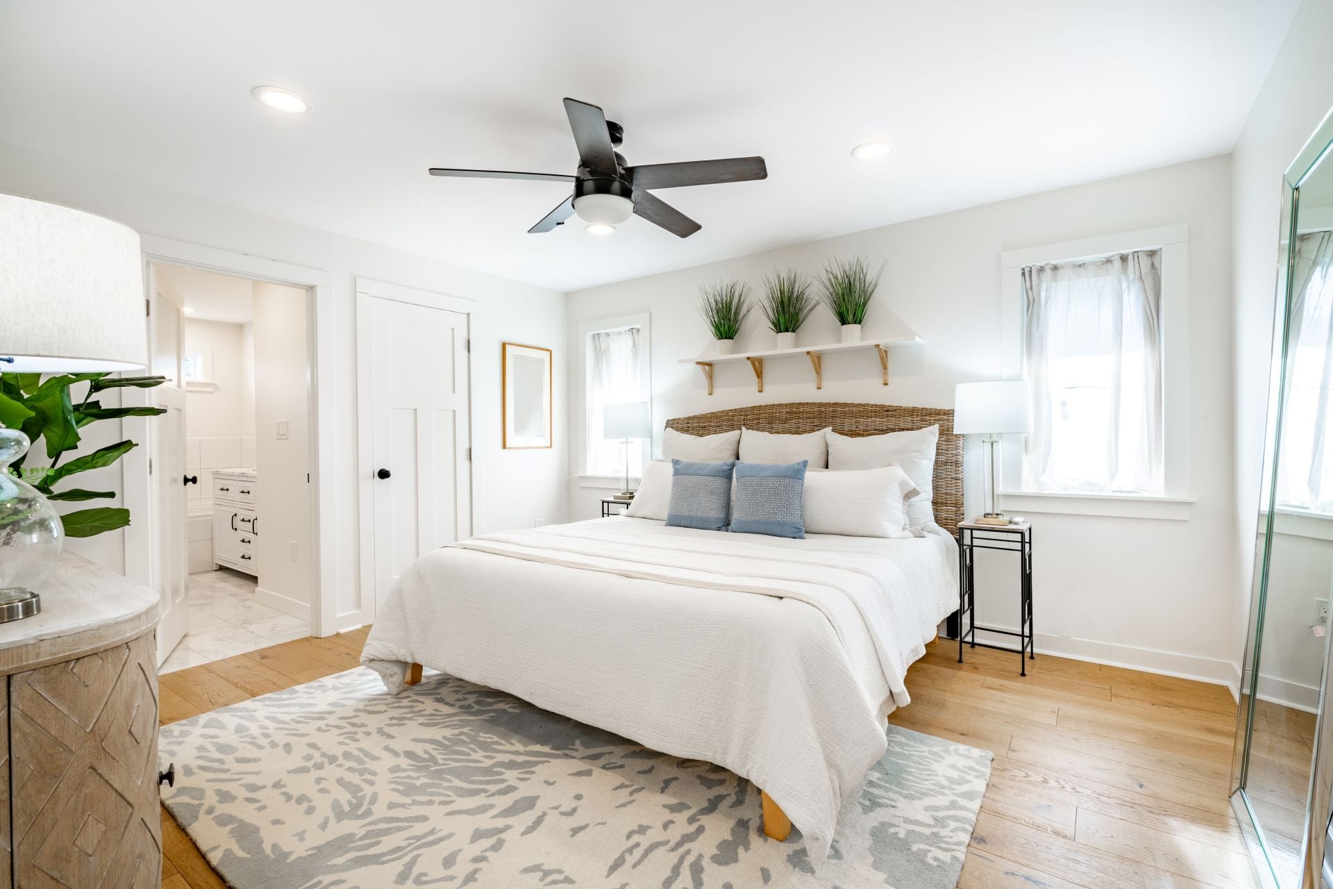 Staged bedroom interior with wooden floors, bright spacious rooms with decor clean crisp linens bedding throw pillows hardwood floors and ocean view