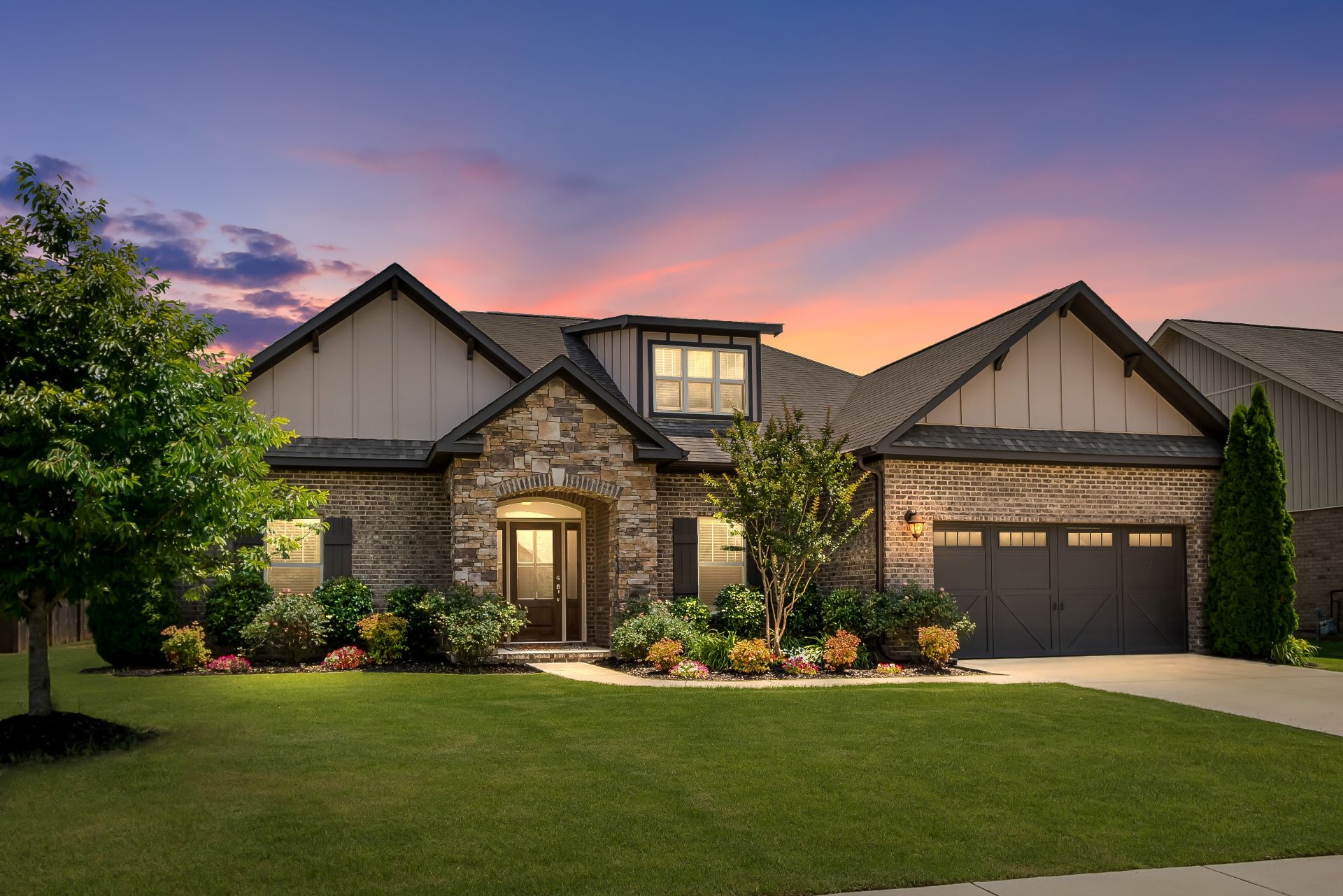 Contemporary Home Exterior with Colorful Sunset. Green Grass, Brick and Stacked Stone, Meticulous Landscaping, Warm and Inviting House. (1)