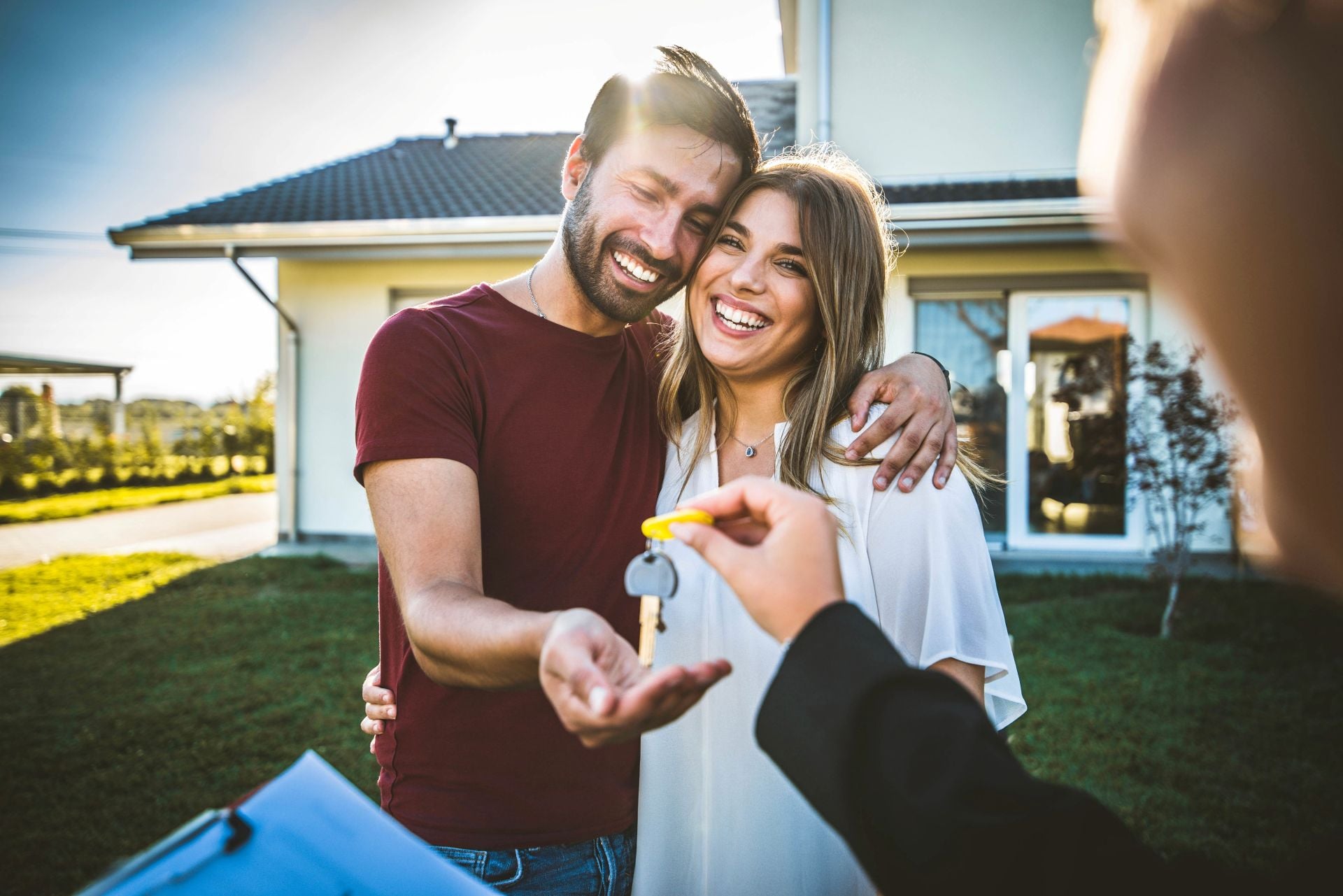 Happy millennial couple receiving keys from realtor, purchasing real estate - Family meeting with real estate agent - New house and real estate concept