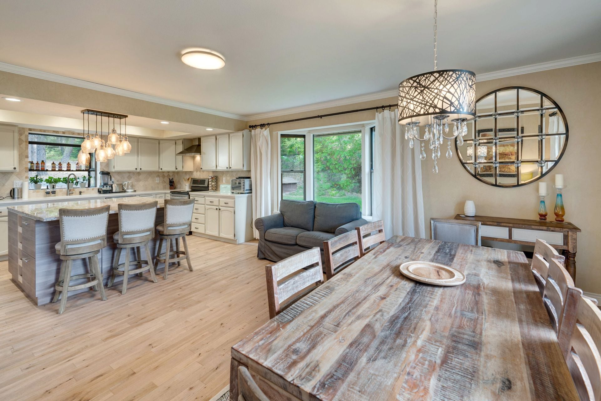 Amazing home interior natural tones with luxury furniture - huge open cozy dining room, kitchen with island, lots of lights, linen chairs, wooden massive table. Wheat venetian plaster, light oak floor