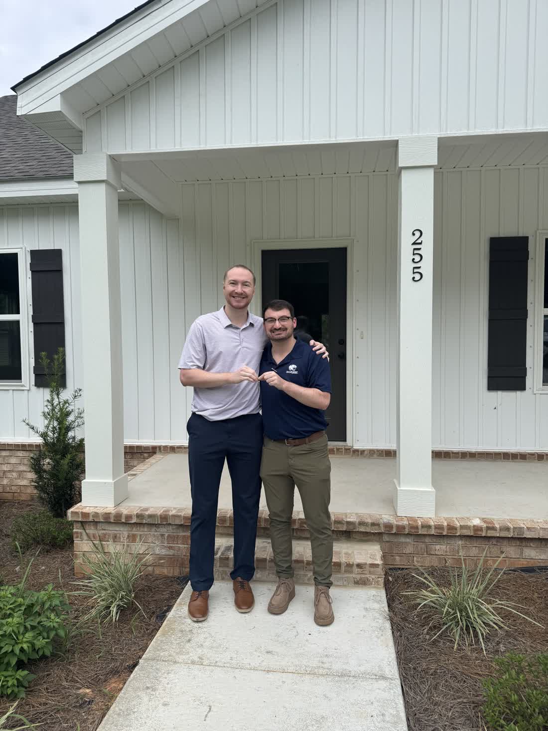Jacob and Zac standing together on the front porch of their new home