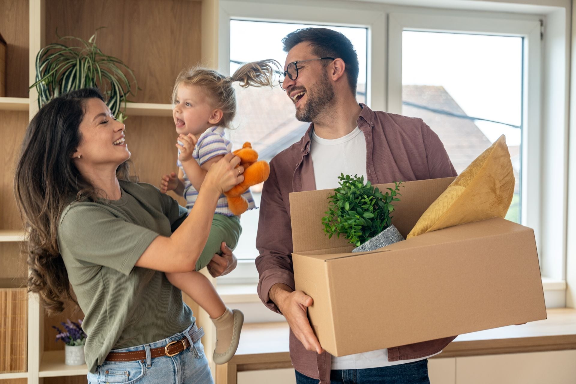 Young couple with their daughter happily moving into their new apartment after buying it with a bank loan.
