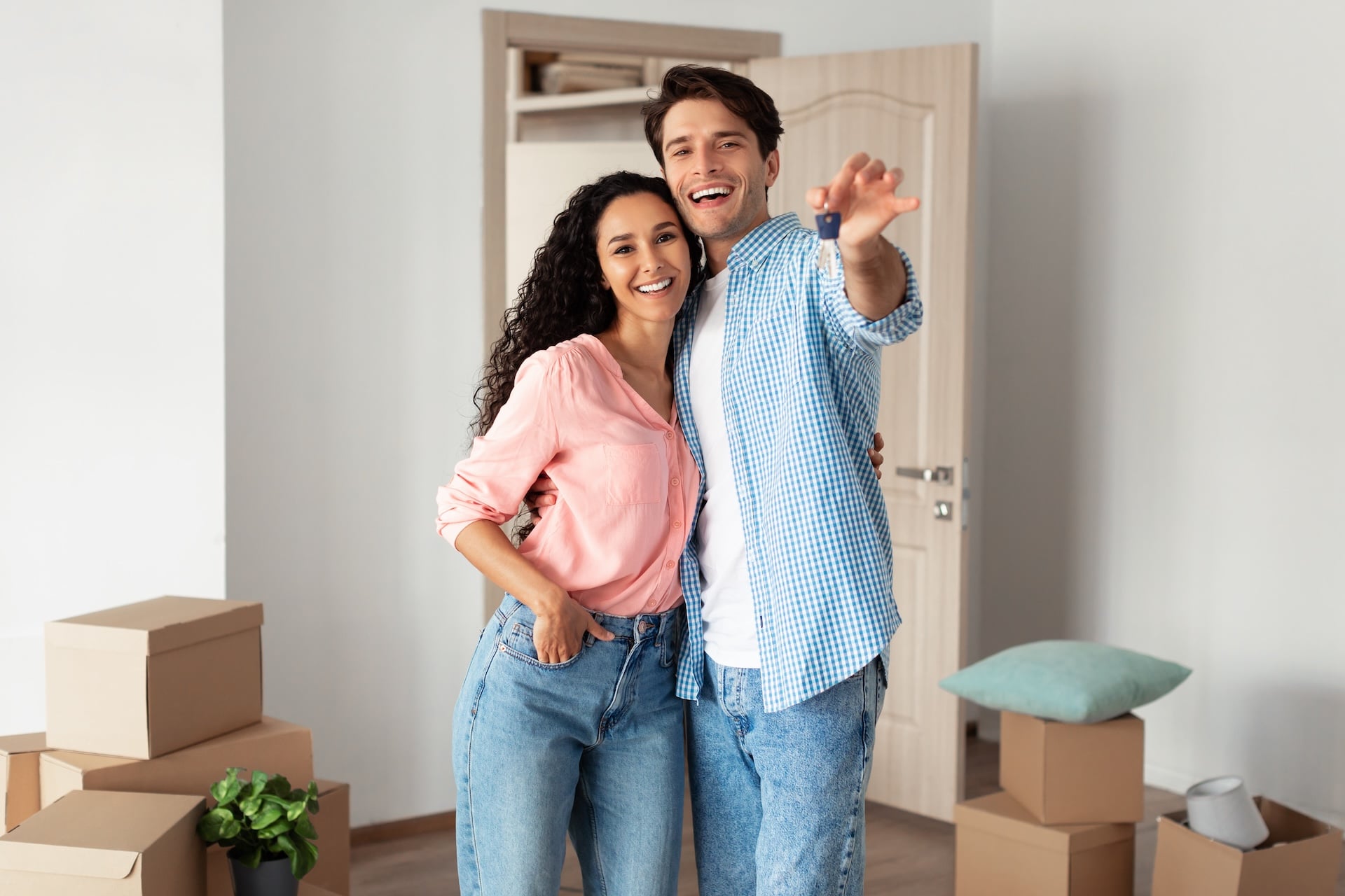 House Ownership. Portrait Of Happy Young Couple Holding Showing Key Standing In New Flat, Cheerful Guy And Lady