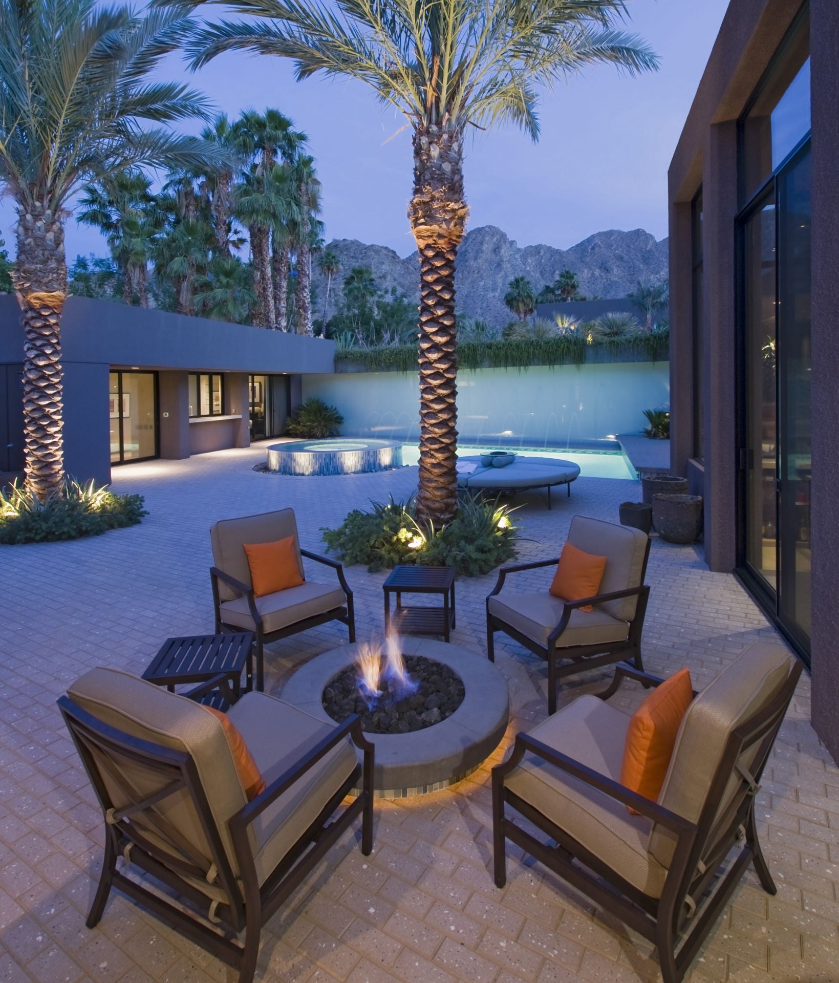 Burning fire pit surrounded by chairs on terrace of California home