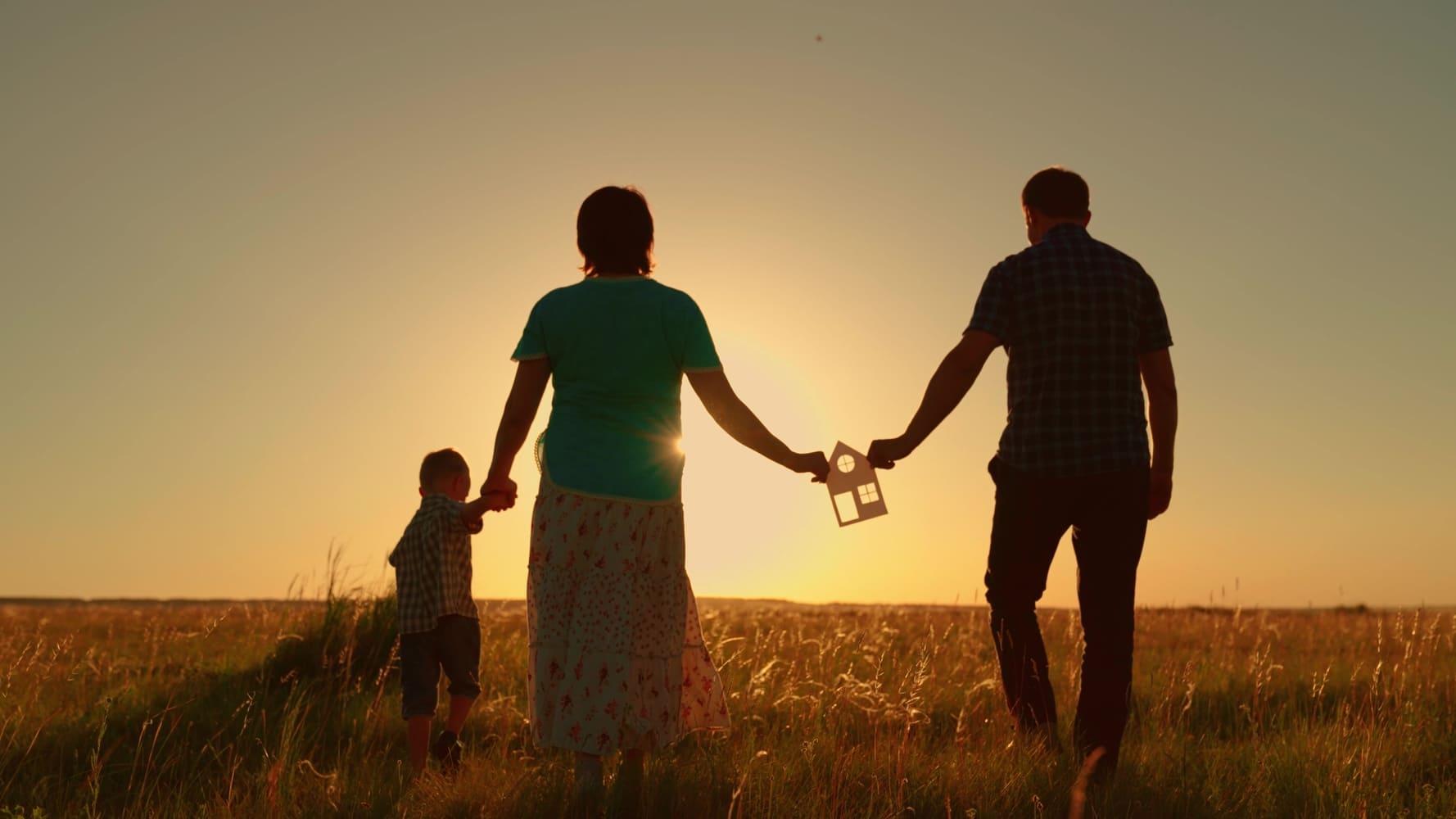 family-holding-house-at-sunset